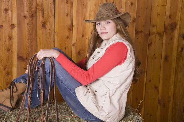 Woman sitting on hay with bridle — Stock Photo, Image