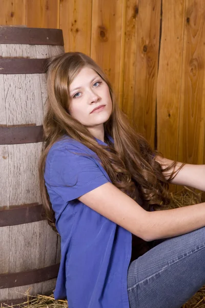 Woman sitting by barrel serious expression — Stock Photo, Image