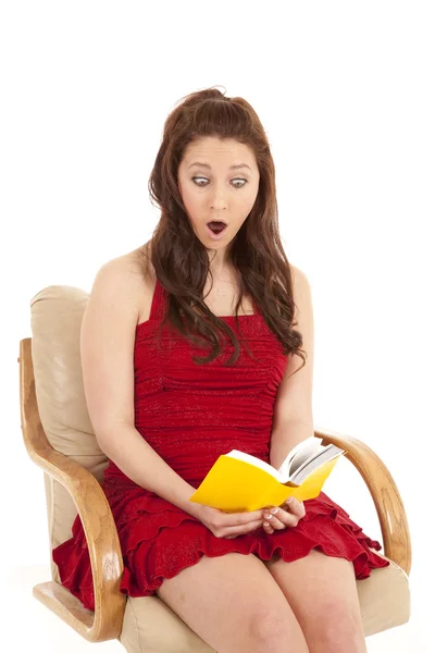 Žena červené šaty kniha sit šokován — Stock fotografie
