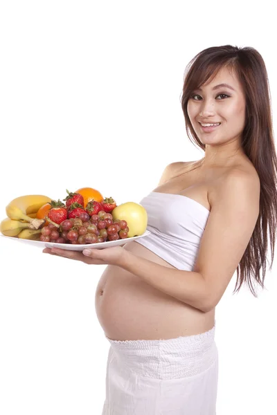 Grávida segurando prato de frutas de pé — Fotografia de Stock