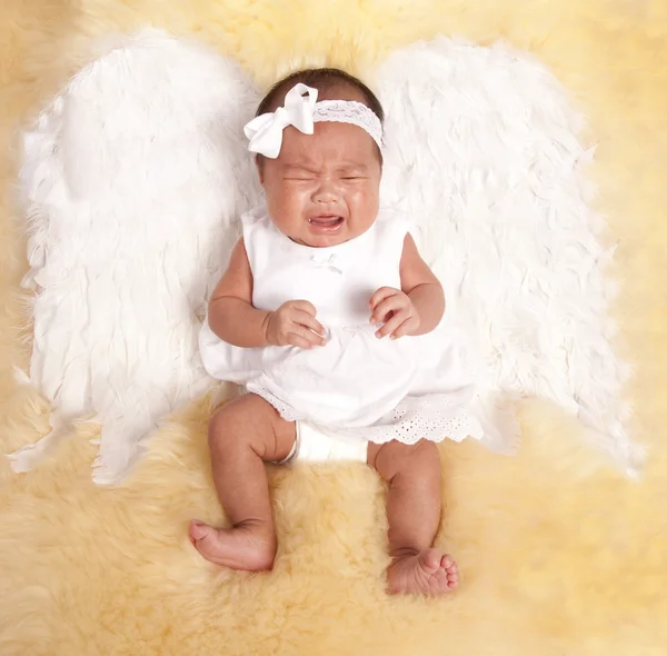 Bebê deitado em um tapete de pele com suas asas de anjo branco — Fotografia de Stock