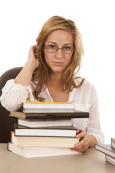 Vrouw op zoek heeft een stapel boeken op tafel — Stockfoto