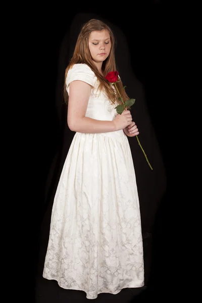 Dívka bílé šaty držet růže a dívat se dolů — Stock fotografie