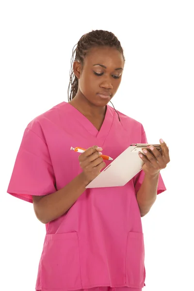 Woman pink scrubs writing down — Stock Photo, Image