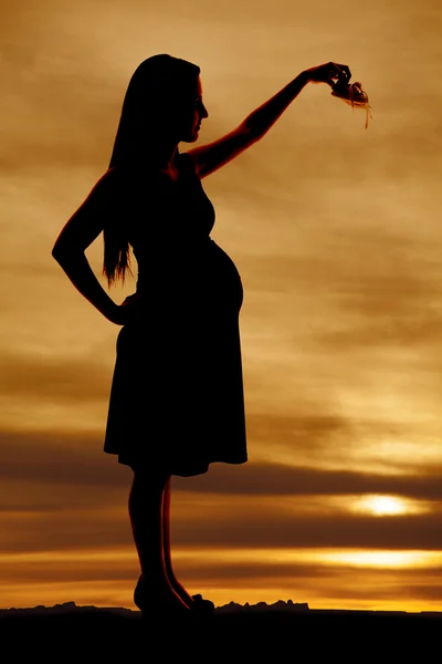 Silhouette pregnant woman holding baby shoes — Stock Photo, Image