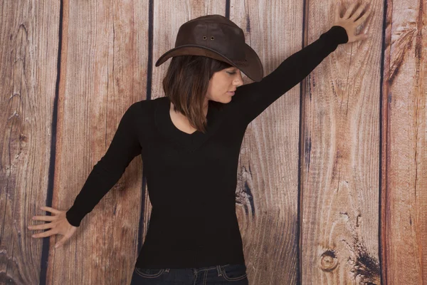 Woman cowgirl wooden wall arms out — Stock Photo, Image