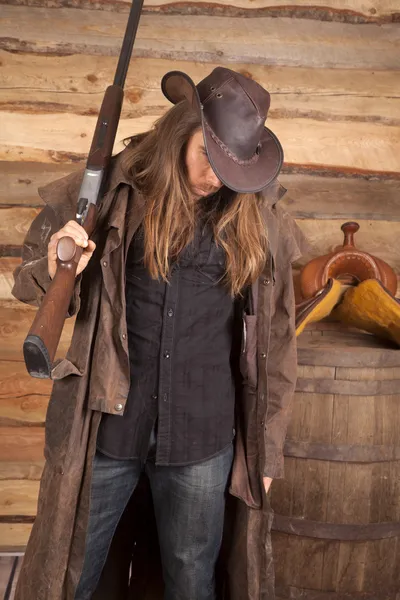 Cowboy duster long hair rifle over shoulder by wall — Stock Photo, Image