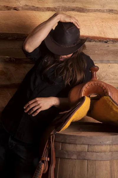 Cowboy in low light hold hat saddle — Stock Photo, Image