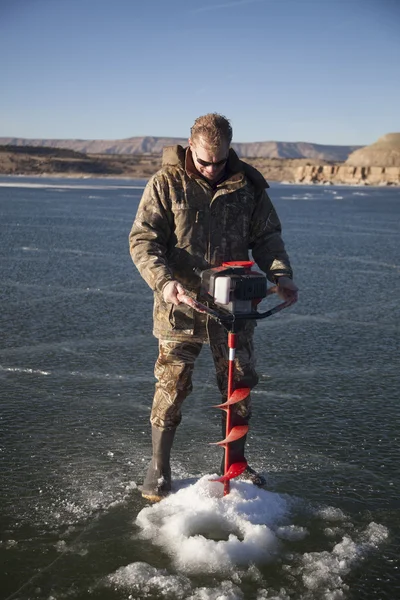 Man in camo drilling hole in ice look down — Stock Photo, Image