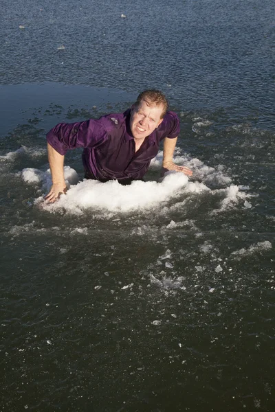 Man in ijsgat klimmen uit — Stockfoto