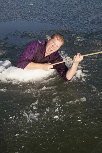 Man in ijsgat uitlichten op touw op zoek — Stockfoto