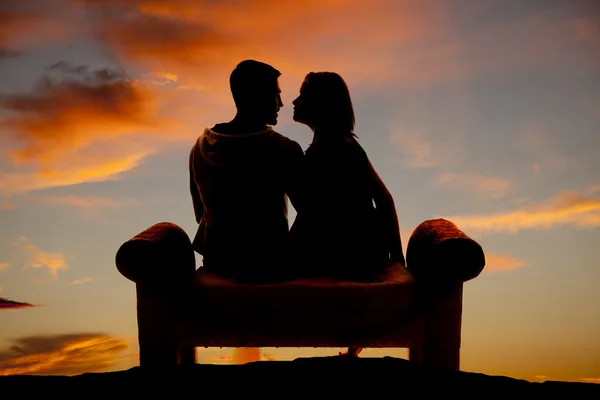 Silhouette couple facing on a bench — Stock Photo, Image