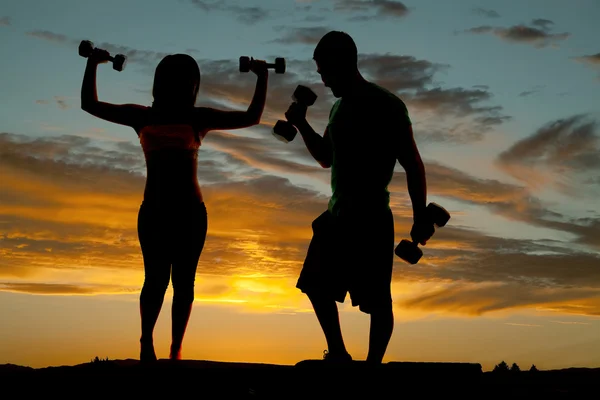 Silhouette couple with weights curl — Stock Photo, Image