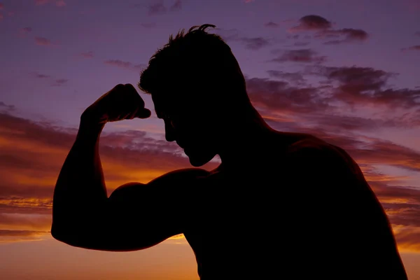 Silhouet van een man in zonsondergang één arm te buigen — Stockfoto