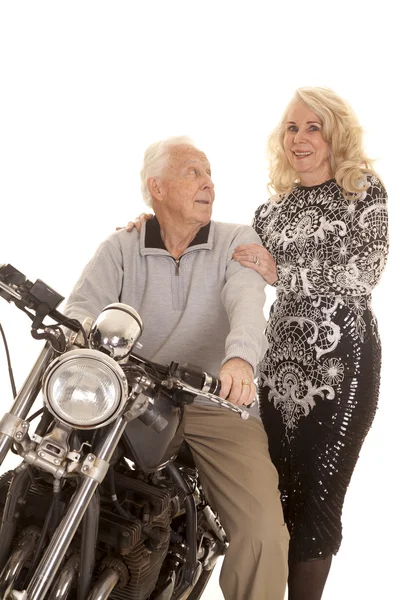 Elderly couple him on motorcycle her stand