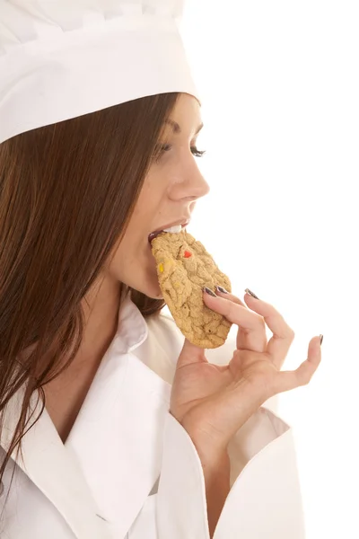 Mujer panadero morder una galleta mirar hacia abajo — Foto de Stock