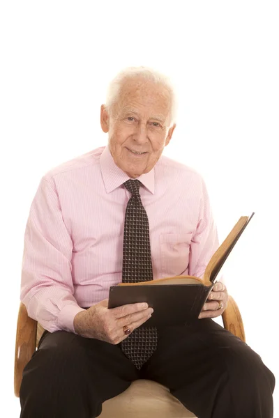 Yaşlı adam pembe gömlek kitap bakmak — Stok fotoğraf