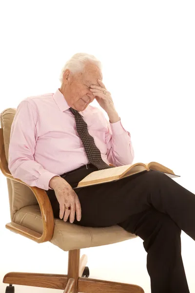 Oudere man roze shirt hand op hoofd boek — Stockfoto