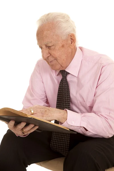 Oudere man roze shirt lezen kant — Stockfoto