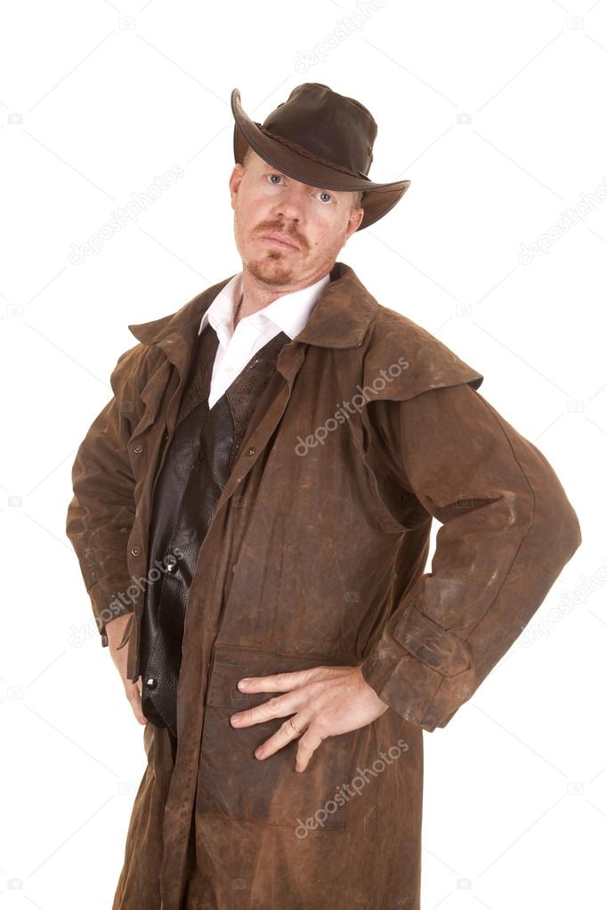 cowboy with hat and duster hands on hips serious