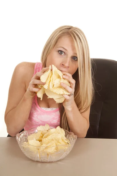 Vrouw roze tank top chips spullen in de mond — Stockfoto