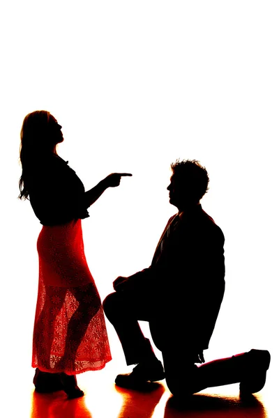 Silhouete man knäböja kvinna pekar på honom — Stockfoto
