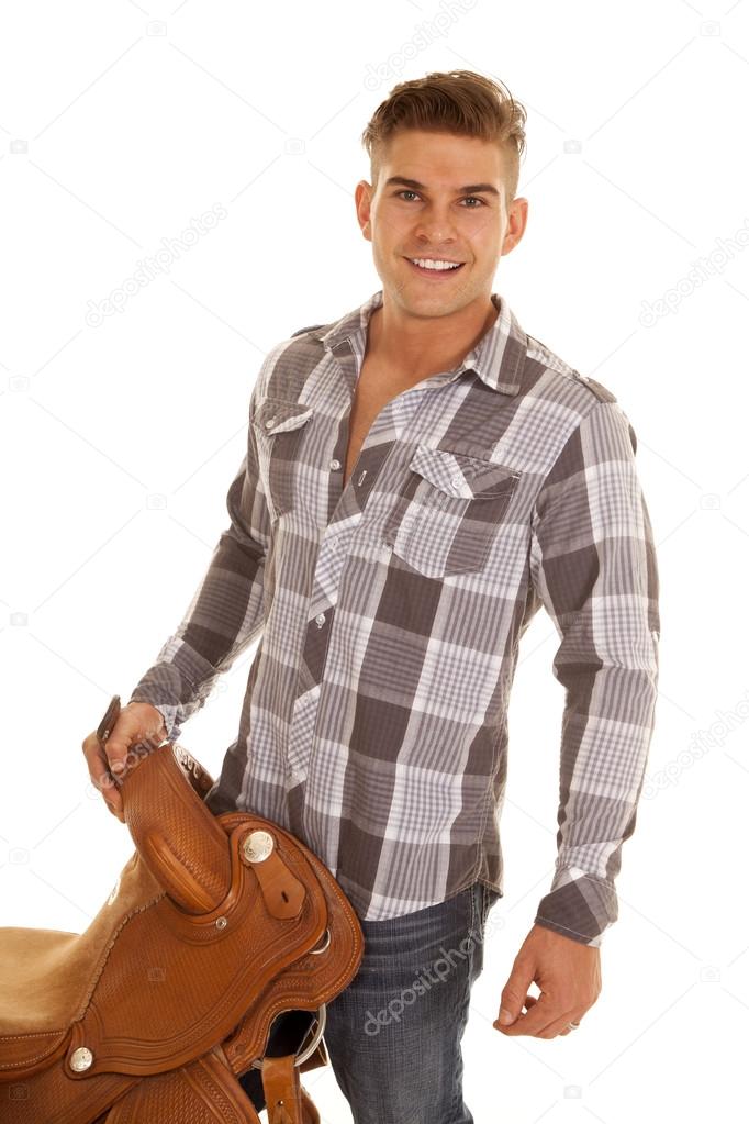 man plaid shirt holding saddle looking smiling