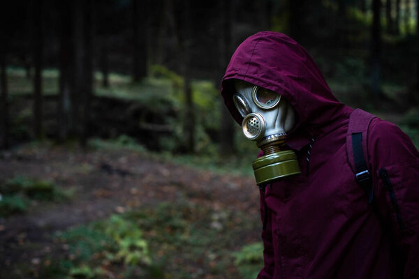 Ecological catastrophy. Post apocalyptic survivor in gas mask. Man at forest.