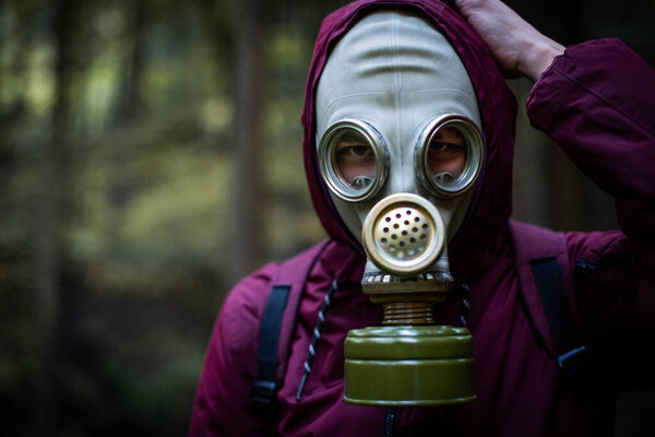 Ecological catastrophy. Post apocalyptic survivor in gas mask. Man at forest.