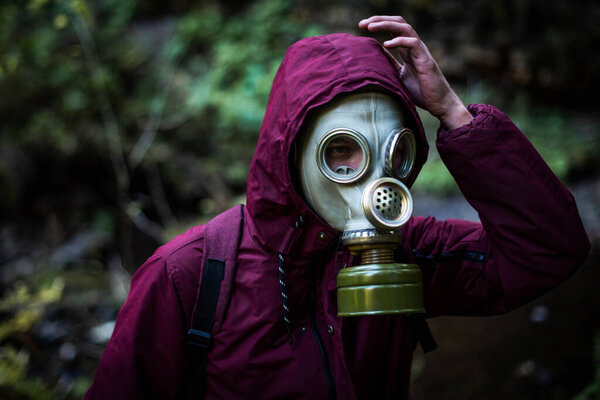 Ecological catastrophy. Post apocalyptic survivor in gas mask. Man at forest.