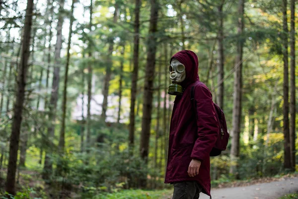 戴着防毒面具站在森林里的一个随意的年轻人 生态多样性 戴防毒面具的末日后幸存者森林里的人 — 图库照片