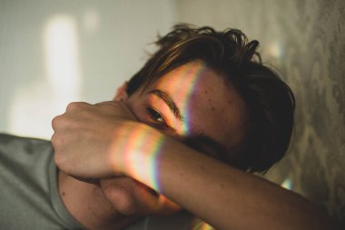 Gözlerinde gökkuşağı gölgesi ve gülümseyen tırnak boyası olan bir adam. LGBT konsepti. Gençlerin sorunları, üzgün çocuk, cilt problemi..