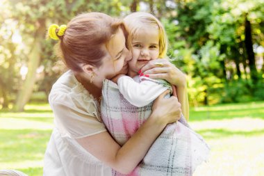 Parkta saman sepeti ve şapkayla piknik yapan güzel bir kız. Bahar güneşli konsept. Anneler Günün kutlu olsun. Sevgi dolu bir aile. Anne ve kızı..