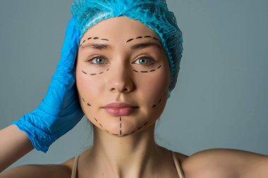 Plastik cerrahi pastel gri arka plan üzerinde izole sonra güzel bir Bayan saf mükemmel kusursuz pürüzsüz parlaklık cilt çizgiler işaretlenmiş gösteren farklı bölüme ayrılmıştır temiz temizlemek yakın çekim portre yerleştirir