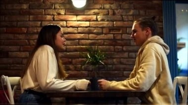 Kafede oturup muhabbet eden tatlı genç erkek ve kız çiftin romantik randevularının keyfini çıkarın. Öğrencilerin iki arkadaşı bir kafede aktif bir duygusal diyalog içindeler.