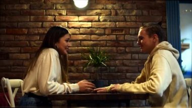 Kafede oturup muhabbet eden tatlı genç erkek ve kız çiftin romantik randevularının keyfini çıkarın. Öğrencilerin iki arkadaşı bir kafede aktif bir duygusal diyalog içindeler.