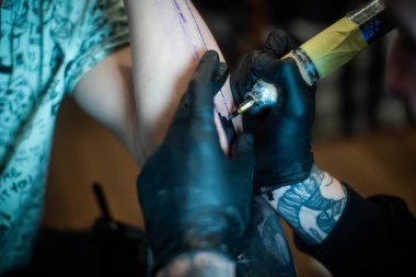 Kuaförde dövmenin kesilip atılmış hali. Profesyonel bir dövme sanatçısı dövme makinesinin iğnesini kullanarak cilde mürekkep yerleştirir. Stüdyoda çalışan profesyonel bir dövmeci..