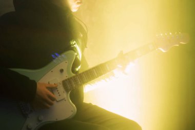Genç adam elektro gitar ile ışık efekti koyu arka plan üzerinde oynamak