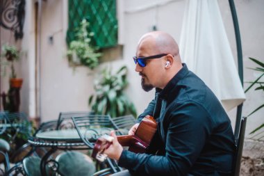 Sokakta gitar çalan güneş gözlüklü ilginç bir sakallı adam. Eski tarz. Yaşam tarzı, gerçek insanlar konsepti..