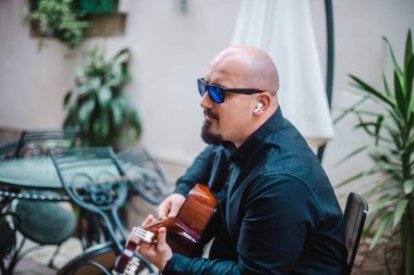Sokakta gitar çalan güneş gözlüklü ilginç bir sakallı adam. Eski tarz. Yaşam tarzı, gerçek insanlar konsepti..