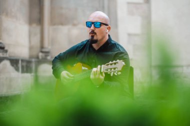Sokakta gitar çalan güneş gözlüklü ilginç bir sakallı adam. Eski tarz. Yaşam tarzı, gerçek insanlar konsepti..