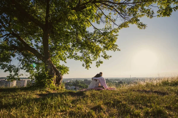 若いカップルの旅行者は山の上の日の出を見ている ウクライナのフィールドで木の下に婚活 — ストック写真