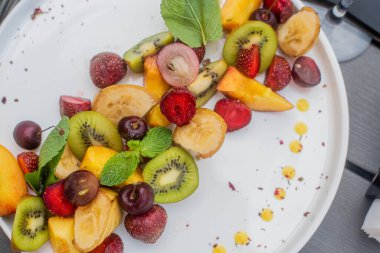 Meyve tabağı. Kivi, muz, kiraz, çilek ve şeftali bir tabakta