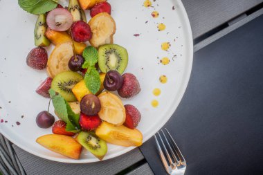 Meyve tabağı. Kivi, muz, kiraz, çilek ve şeftali bir tabakta