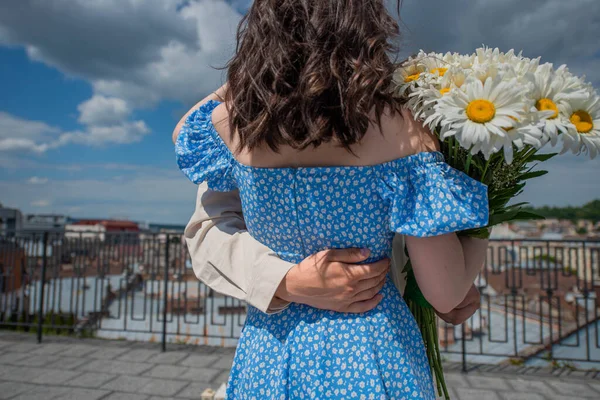 Жених Обнимает Мягко Поддерживает Невесту Синем Платье Маргаритками Сзади Фон — стоковое фото
