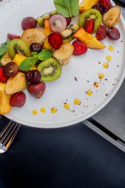 Meyve tabağı. Kivi, muz, kiraz, çilek ve şeftali bir tabakta