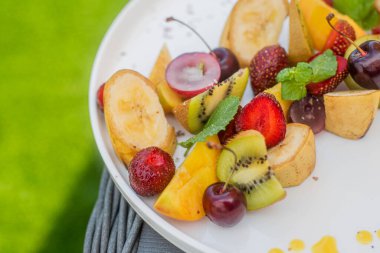 Meyve tabağı. Kivi, muz, kiraz, çilek ve şeftali bir tabakta
