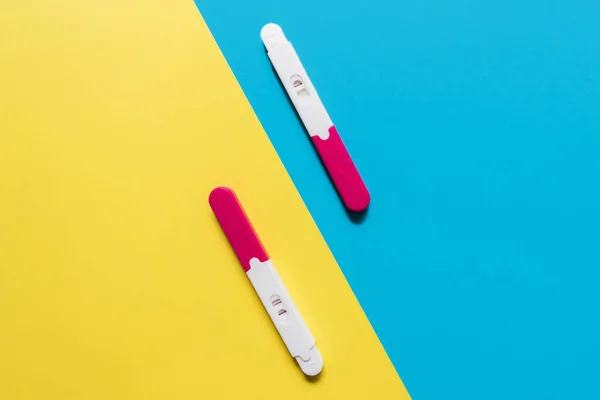 positive and negative pregnancy tests on blue and yellow backgrounds