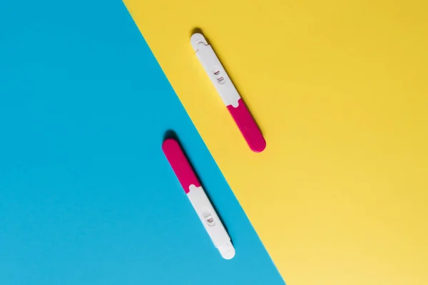positive and negative pregnancy tests on blue and yellow backgrounds