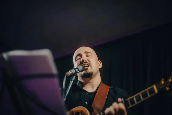 guitarist man playing guitar and singing a song at a concert